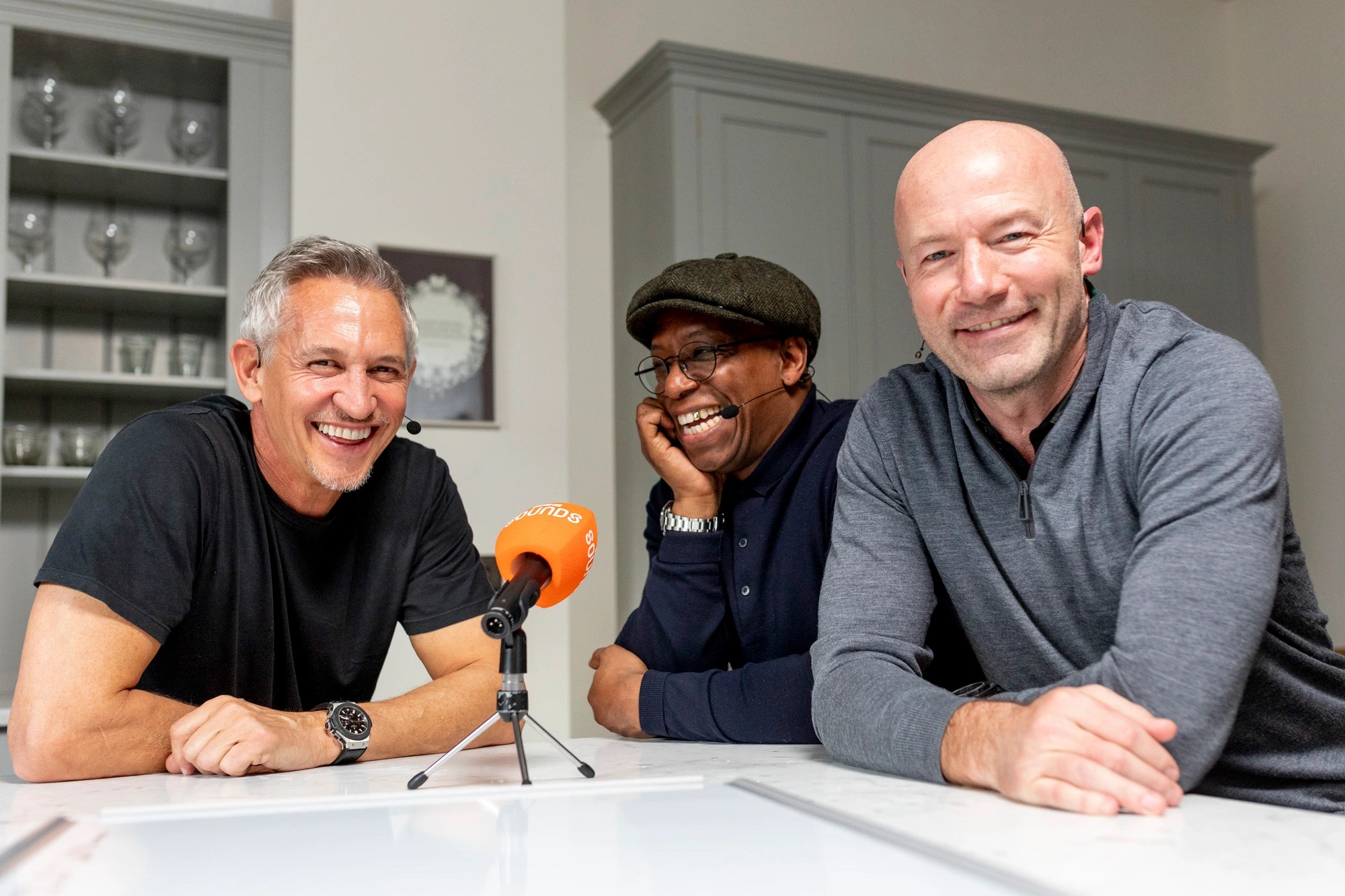 Gary Lineker, Ian Wright, and Alan Shearer at a microphone.