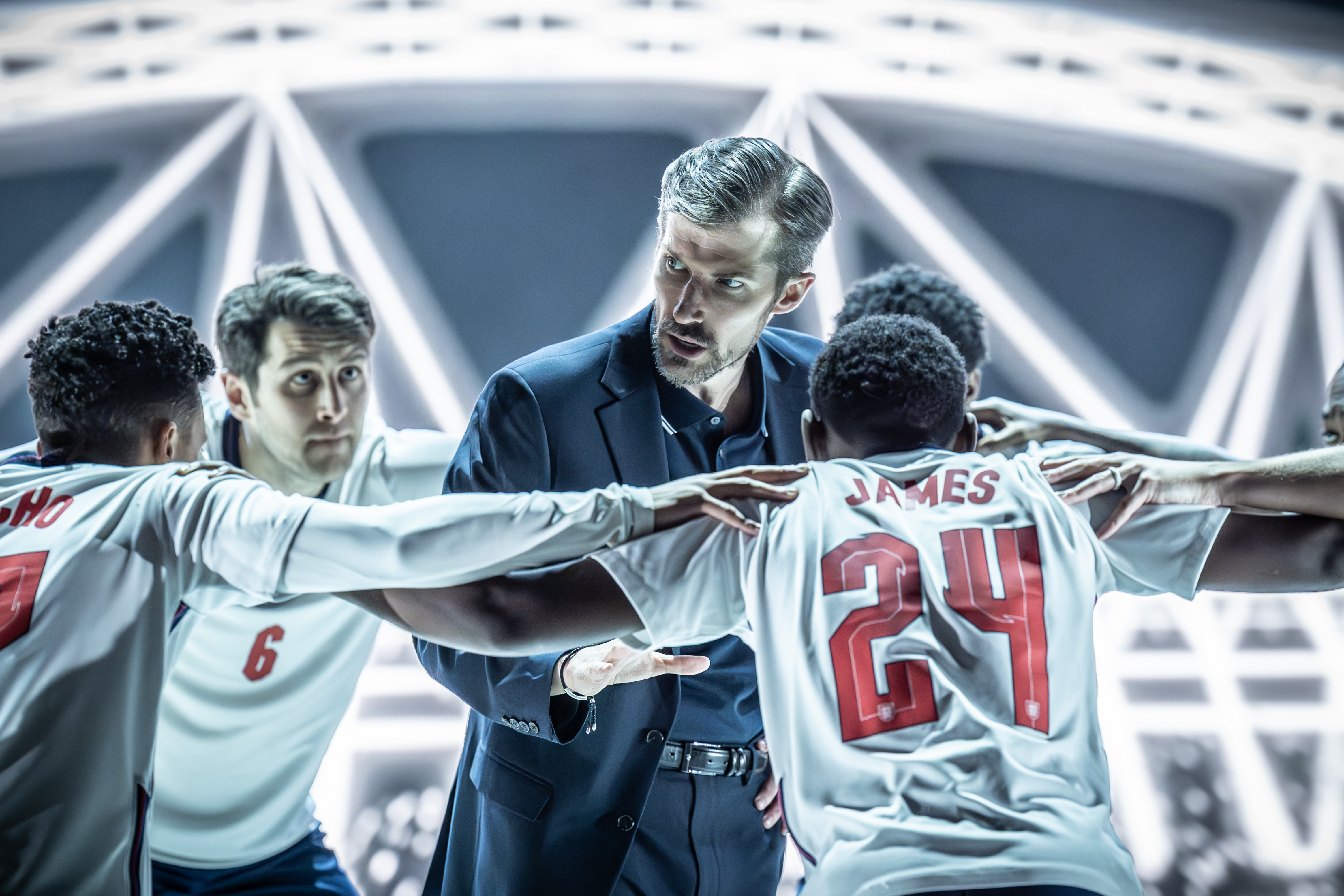 A scene from Dear England, depicting a soccer coach and players.