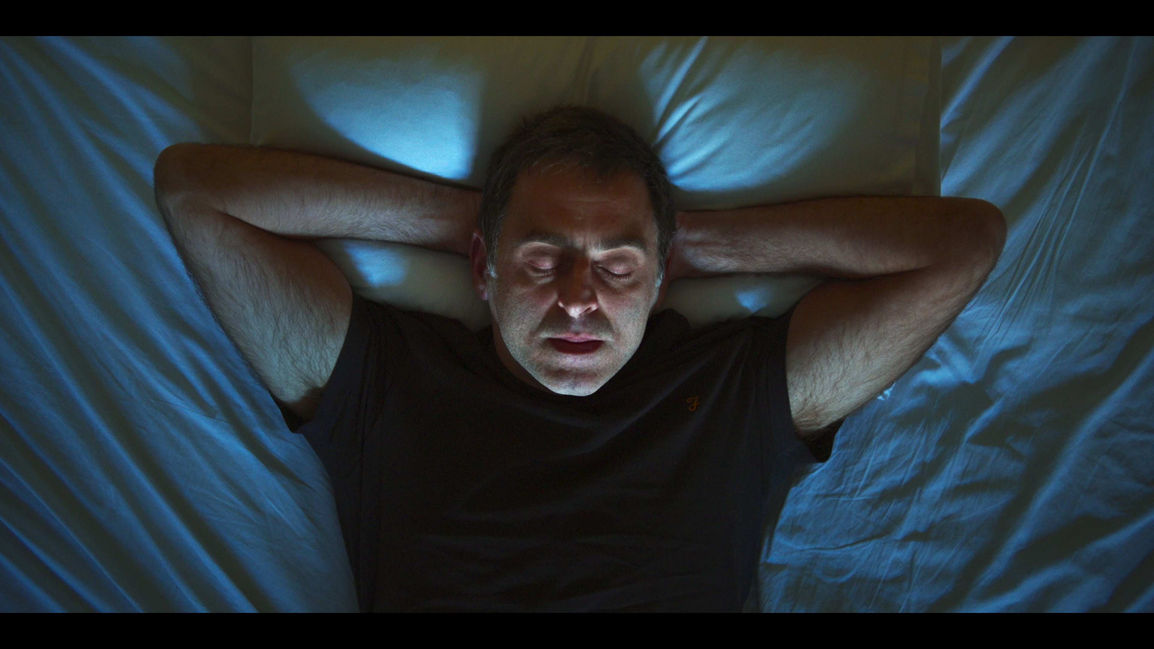 a man laying on a bed with his eyes closed