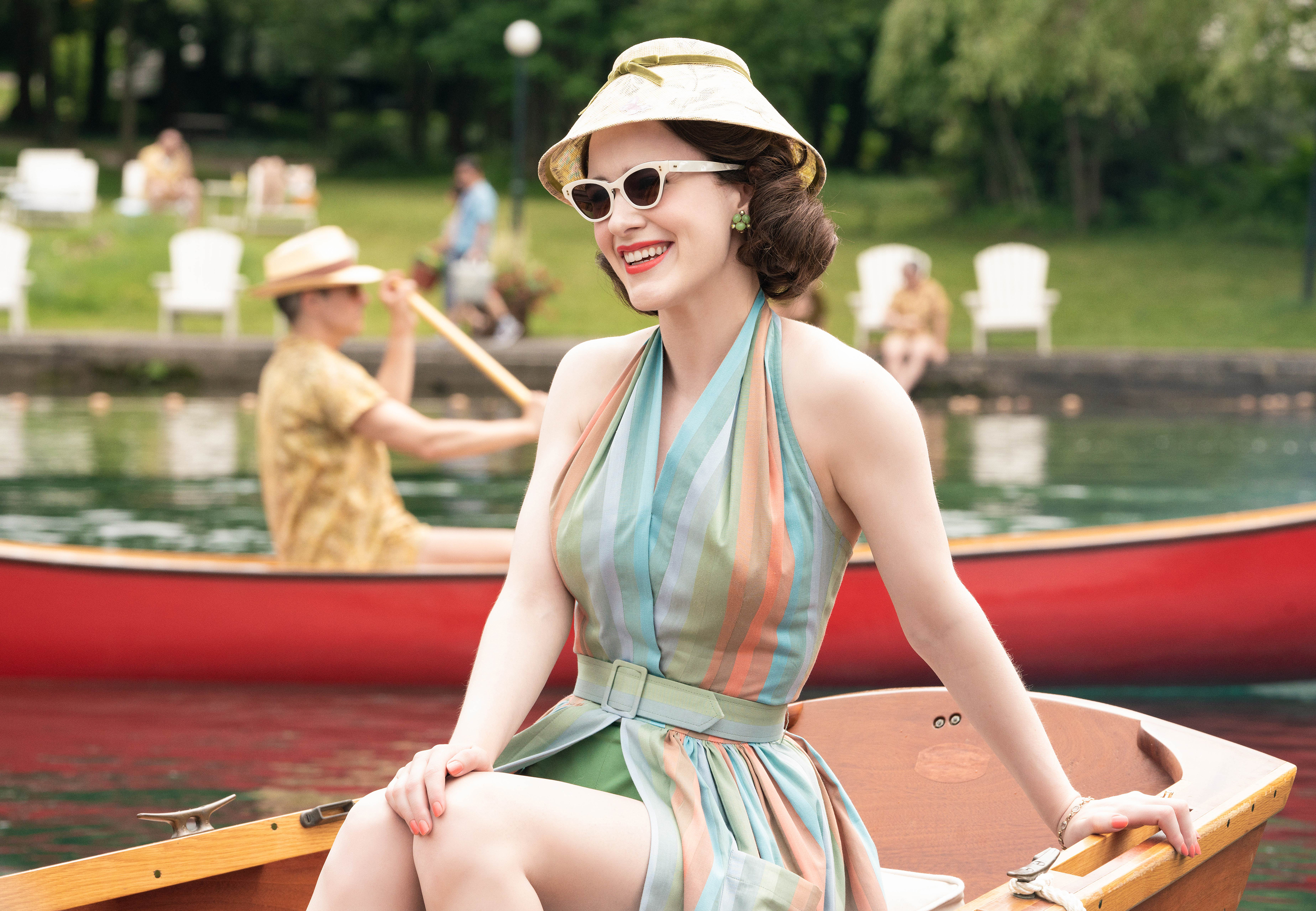 a woman wearing sunglasses and a hat sits in a boat