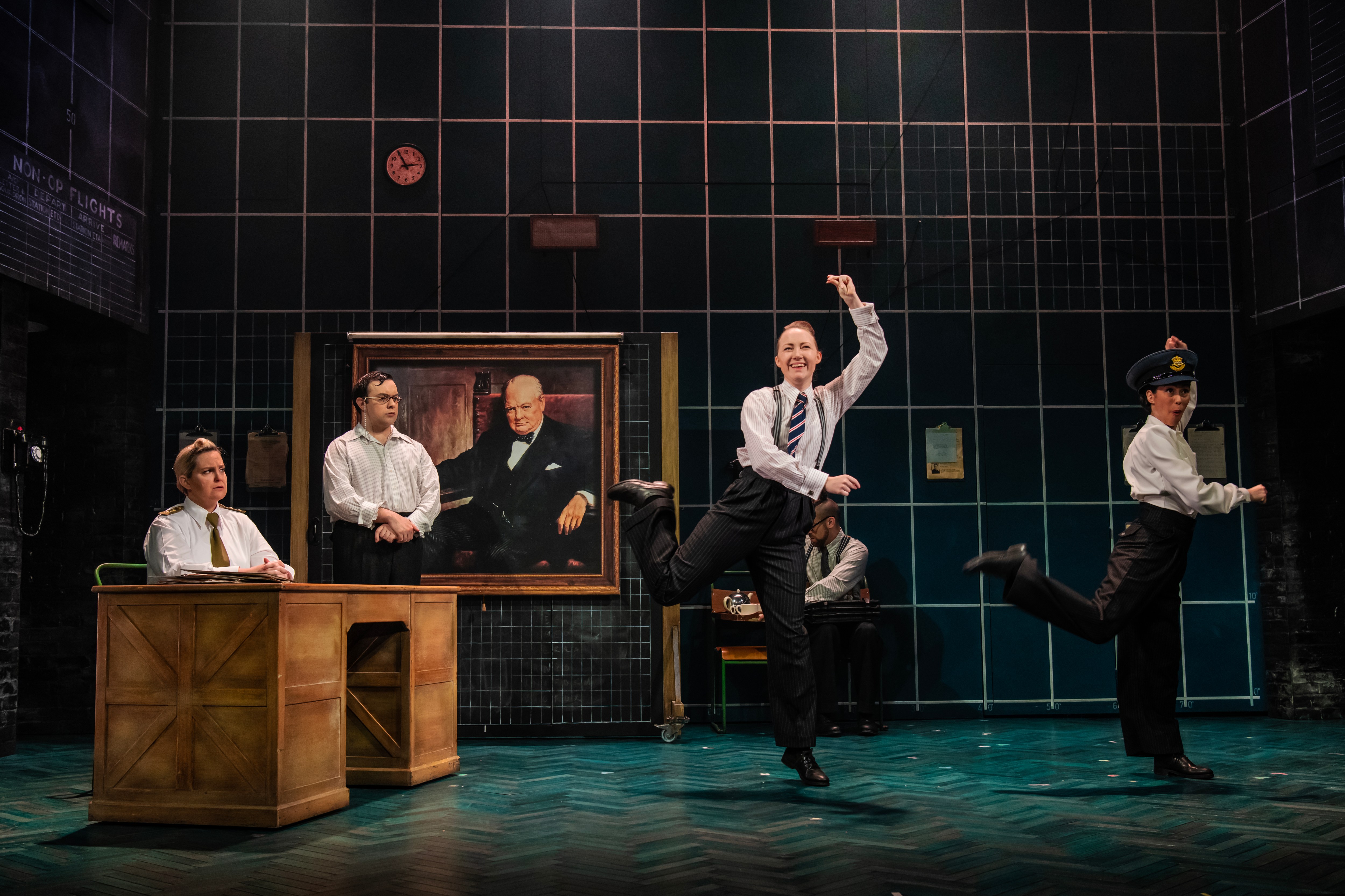 a group of performers on stage in front of a painting
