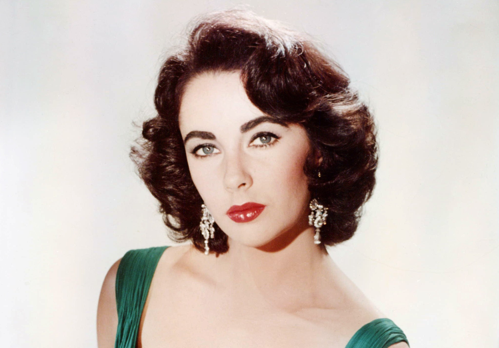 Elizabeth Taylor in a green dress and white fur wrap.