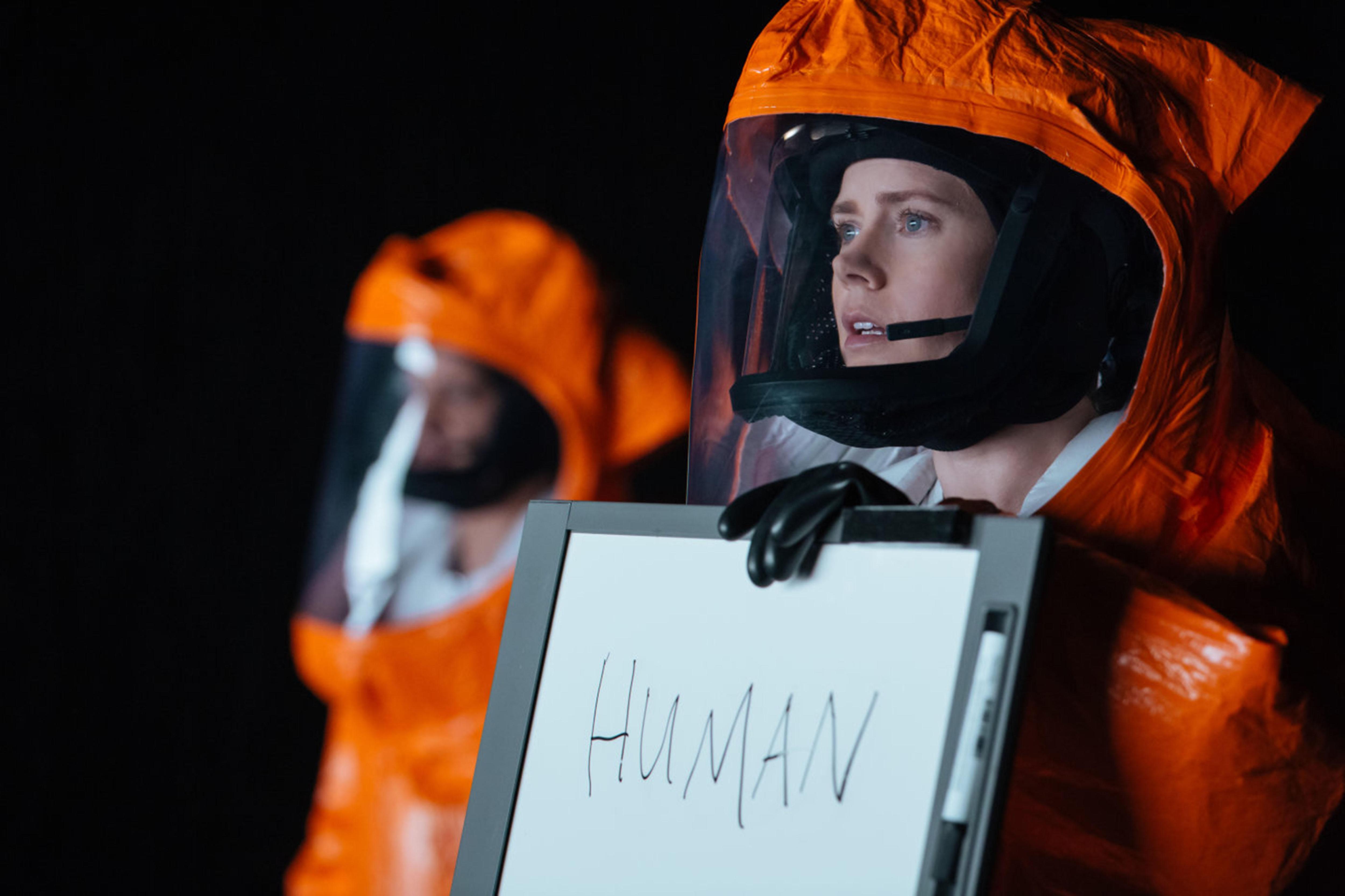 A linguist communicates with aliens in a hazmat suit.